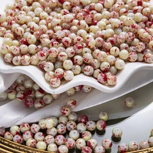 Gros plan de perles en porcelaine blanche avec des éclaboussures rouges pour bijoux DIY
