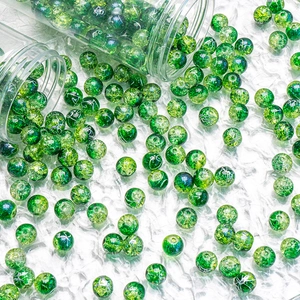 Close-up of 10mm green cracked glass beads pouring from a jar for DIY jewelry making