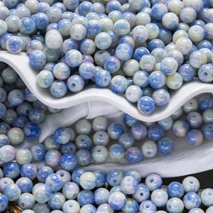 Gros plan de perles en céramique peintes à l'aquarelle bleue et blanche pour bijoux