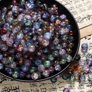 Macro detail of 10mm colorful cracked glass beads with gold accents in a ceramic bowl