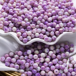 Détail de perles en céramique marbrées violettes avec effet encre pour bijoux DIY