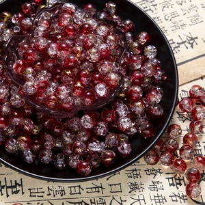 Macro shot of 10mm red cracked glass beads with gold wire details in a ceramic plate