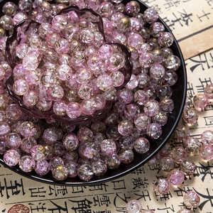Macro shot of 10mm pink glass crackle beads with gold wire textures for DIY jewelry