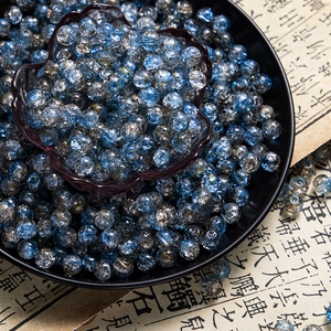 Macro shot of 10mm blue cracked glass beads with silver foil on Chinese calligraphy paper