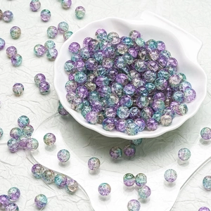 Macro detail of 10mm purple and green crackle glass beads in a white shell bowl