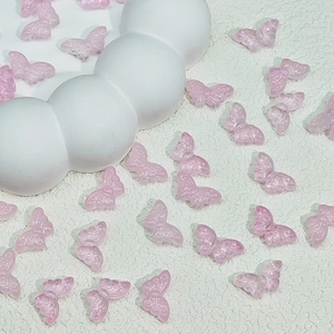 Macro detail of translucent pink butterfly resin beads with fine wing texture for DIY crafts