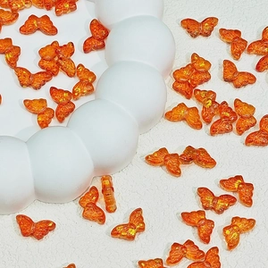 Macro view of bright orange translucent butterfly beads with gold foil for DIY crafts