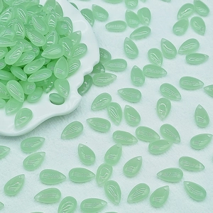 Macro shot of 8x14mm pale green teardrop glass beads in a white ceramic dish for DIY jewelry