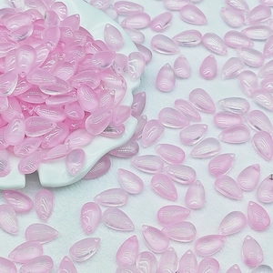 Pink teardrop glass beads displayed in a white ceramic dish for jewelry making