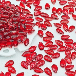 Detailed view of red teardrop glass beads in a porcelain dish for DIY jewelry making