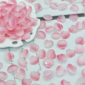 Detailed view of pink gradient seashell glass beads in a white scalloped ceramic dish