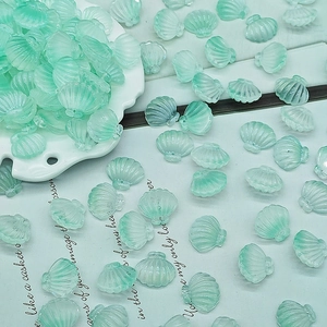 Detailed view of mint green seashell beads for handmade jewelry on a white plate