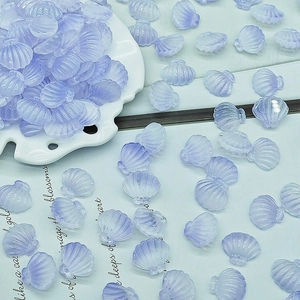 Macro view of lavender purple scallop shell beads for DIY jewelry making on white porcelain plate