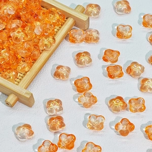 Macro detail of 10mm orange frosted glass flower beads with gold glitter for DIY jewelry
