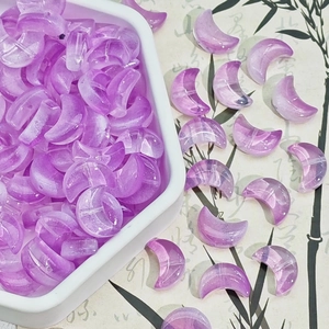 Macro detail of translucent purple moon-shaped beads with holes for DIY jewelry making