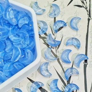 Close-up of translucent blue moon-shaped glass beads for DIY jewelry making and crafts