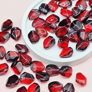 Macro shot of faceted dark red glass beads for DIY jewelry making on a pink background