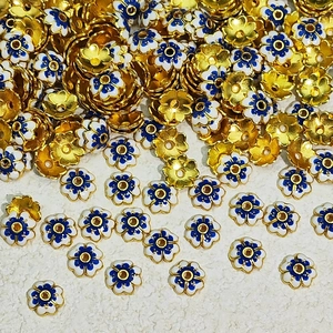 Detail of DIY jewelry spacer beads with gold finish and blue enamel floral pattern