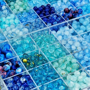 Sortiment blauer Glasperlen mit matten und rissigen Texturen in einer transparenten Box