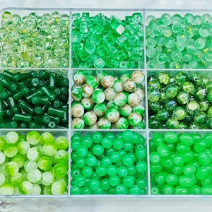 Macro view of green glass bead set in 9-grid box for DIY jewelry making and crafts