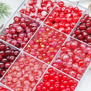DIY bead set with assorted red and pink glass beads in a clear 9-compartment storage box