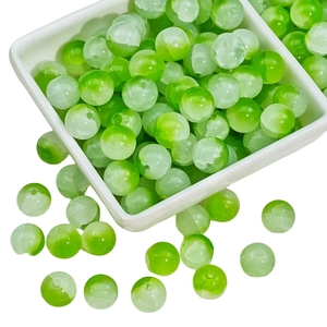 Green and white gradient glass beads for DIY jewelry making displayed on a white tray