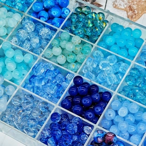 Macro view of blue glass beads assortment in clear storage box for DIY jewelry making