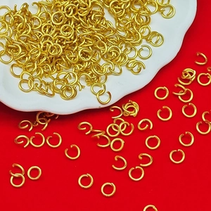 Bulk gold open jump rings for DIY jewelry making displayed on a plate and red base