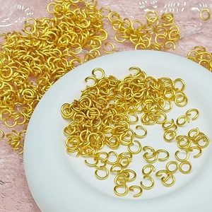 Matte gold jump rings for DIY jewelry making displayed on a decorative round plate