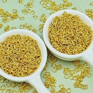 Close-up of golden jump rings in ceramic spoons for DIY jewelry making accessories
