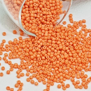 Macro-opname van glanzende oranje glaskralen die op een witte achtergrond vallen
