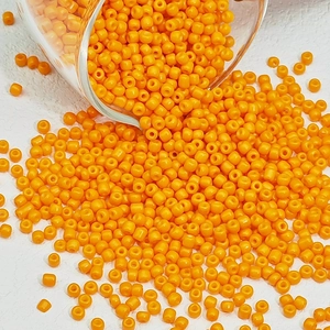 Macro-detail van feloranje ronde glazen kralen die uit een glazen container worden gegoten