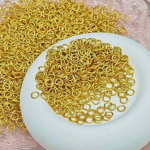Close-up of bright gold open jump rings for DIY jewelry making displayed on a plate
