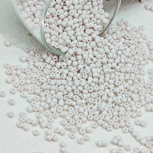 Detailopname van lichtroze glazen kralen op witte getextureerde ondergrond voor DIY sieraden