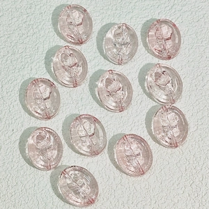 Makro-Detail von ovalen rosa Glasperlen mit geprägten Rosenmustern für DIY-Schmuckherstellung