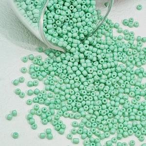 Detail van mintgroene glaskralen die uit een glazen pot stromen voor DIY-sieraden