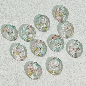 Makroaufnahme ovaler Glasperlen mit rosa Rosen und Goldfolie für DIY-Schmuckdesign