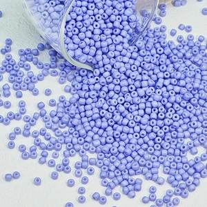 Macro-opname van lichtpaarse lavendel glazen kralen die uit een glazen beker vallen