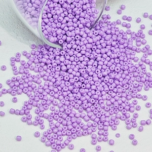 Macro-opname van paarse glazen kralen die op een witte ondergrond vallen voor DIY-projecten