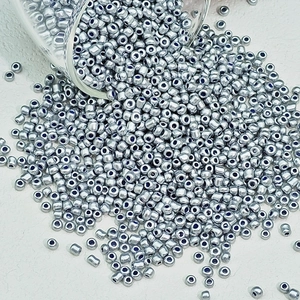 Detailopname van zilveren glaskralen die uit een pot vallen voor DIY-sieraden maken