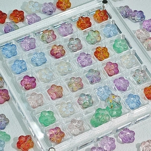 Colorful translucent cherry blossom flower beads in a grid organizer box for jewelry making