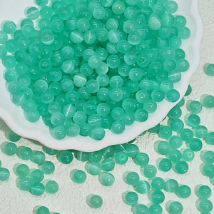 Macro shot of mint green cat eye glass beads with cat-eye effect for DIY jewelry making