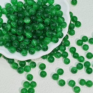 Macro shot of 8mm emerald green cat eye beads in a ceramic dish for DIY jewelry making