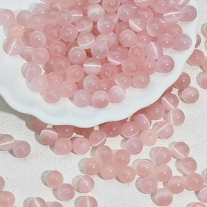 Macro shot of pink cat eye glass beads with luminous fiber optic effect for DIY jewelry