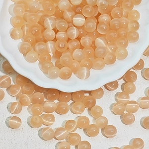 Macro shot of orange cat eye beads in a ceramic bowl for DIY jewelry making crafts