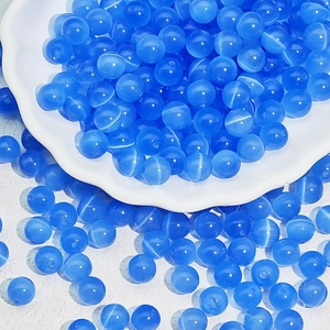 Macro detail of blue cat-eye glass beads for DIY jewelry making on a white ceramic plate