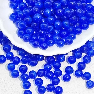Macro shot of 6-10mm deep blue cat eye glass beads for DIY jewelry making in a white dish