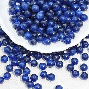 Macro shot of dark blue cat eye stone loose beads in a white petal-shaped ceramic tray