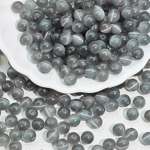 Macro shot of grey cat eye glass beads with vertical light bands for jewelry making