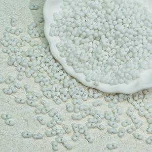 Detailed view of white peanut seed beads in a ceramic bowl for jewelry DIY
